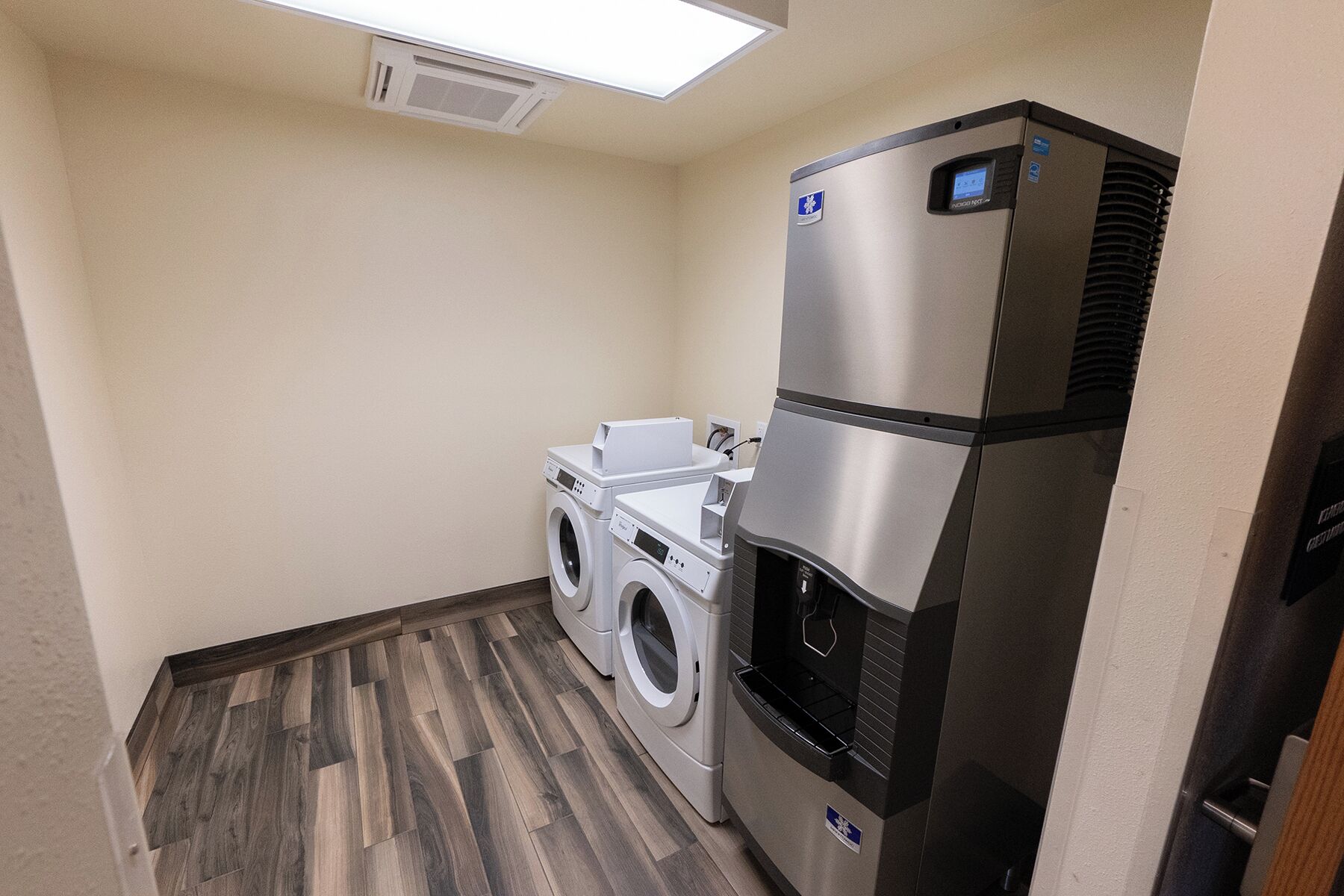 Une petite buanderie équipée d’un lave-linge, d’un sèche-linge et d’un réfrigérateur en acier inoxydable.