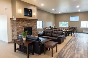 A spacious indoor area with a stone fireplace, leather seating, and a projection screen on the wall.
