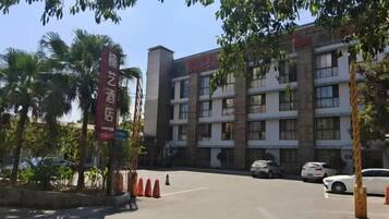 A multi-story hotel with a parking lot and a few cars.
