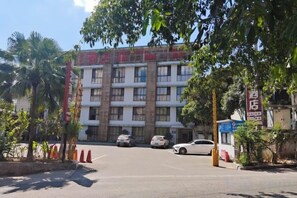 Edifício com vários andares e área de estacionamento na frente.