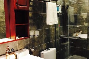 A modern bathroom with a marble wall, a red cabinet, a white sink, and a glass shower enclosure. - Nanyi Hotel (Chishui)
