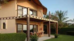 A two-story house with a balcony, a dining area with wooden furniture, and a well-maintained garden. - Les Alizés Cap Skirring (Cap Skirring)