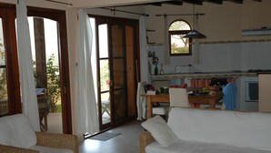 A living room with a sofa, a dining table, and a kitchen area with a stove and sink. - Les Alizés Cap Skirring (Cap Skirring)