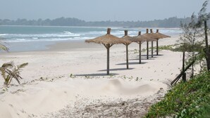 A beach with thatched umbrellas and a sandy shoreline. - Les Alizés Cap Skirring (Cap Skirring)