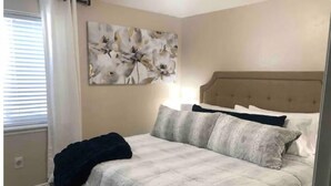 Ein Schlafzimmer mit Bett, Kopfteil und Wandbild.