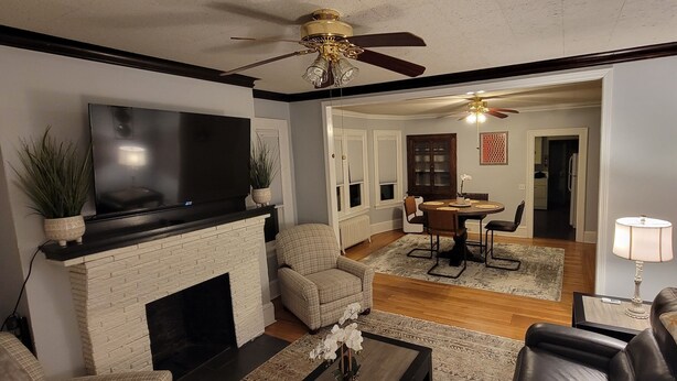 A living room with a fireplace, television, and a dining area with a table and chairs. - SalsVista 1st Floor Corner Apt (Worcester)