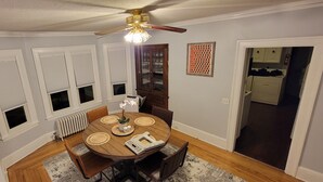 A dining room with a wooden table, chairs, a ceiling fan, and a radiator. - SalsVista 1st Floor Corner Apt (Worcester)
