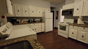 A kitchen with white cabinets, a microwave, a stove, and a refrigerator. - SalsVista 1st Floor Corner Apt (Worcester)