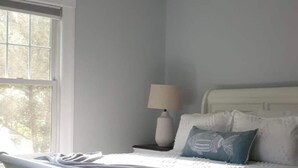 A bedroom with a white bed, a ceiling fan, a window, and a nightstand with a lamp. - SalsVista 1st Floor Corner Apt (Worcester)