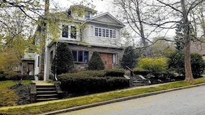 A two-story house with a stone facade, a front porch, and a well-maintained lawn. - SalsVista 1st Floor Corner Apt (Worcester)