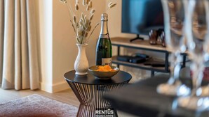 A modern living room with a round black table, a vase with dried plants, a bottle of champagne, and a bowl of snacks. - Seagusta - sea view apartment in Middelkerke (Middelkerke)