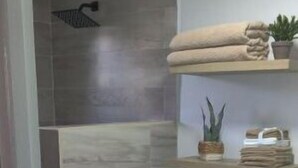 Een moderne badkamer met douche, toilet en wastafel.