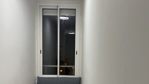 Un pasillo estrecho con un sofá gris y una manta roja.