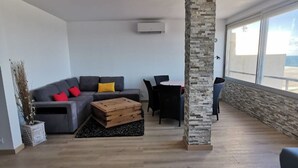 Amplia sala de estar con sofá gris, mesa de centro de madera y una pared de acento de piedra.