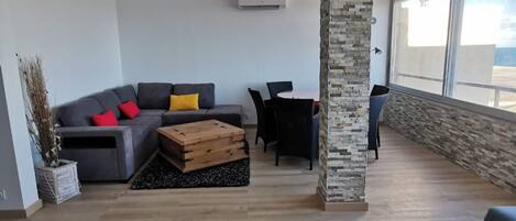 A spacious living area with a grey sofa, wooden coffee table, and a stone accent wall.