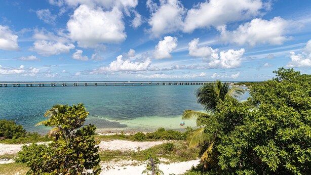 A coastal landscape with a clear view of the ocean, a bridge, and lush greenery. - Ocean Front, Private home with Boat Dock, 3 bedroom (Key West)