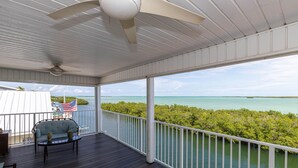 A covered outdoor deck with a ceiling fan, a sofa, and a table. - Ocean Front, Private home with Boat Dock, 3 bedroom (Key West)