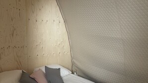 A bed with a quilted white duvet, pillows in various shades, and a wooden headboard.