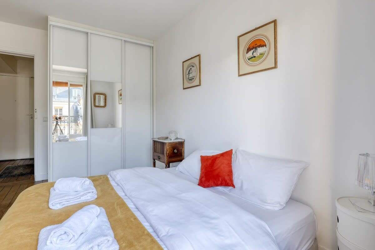 A hotel room with a bed, a bedside table, a nightstand, and a window.