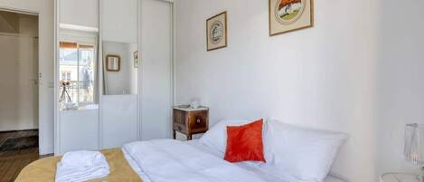 A hotel room with a bed, a bedside table, a nightstand, and a window.