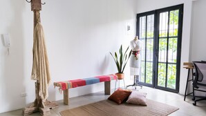 Une pièce comprenant un banc, une corde suspendue, une plante en pot, un mannequin et une grande fenêtre.