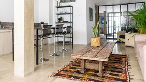 Ein modernes Wohnzimmer mit einem Holztisch, einem gemusterten Teppich und einer Topfpflanze.