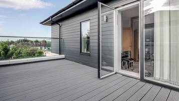 A modern building with a grey exterior, a balcony with a glass door, and a view of the surrounding area.