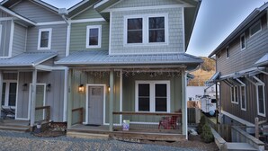 A two-story house with a porch, a front door, and a garage. - Walk to Train! Pet-Friendly Townhome! (Bryson City)