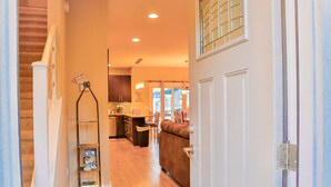 A hallway leading to a kitchen with wooden flooring, a staircase, and a door with a metal latch. - Walk to Train! Pet-Friendly Townhome! (Bryson City)