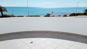 Un patio con baldosas y borde curvo, con vistas a una playa y al océano.