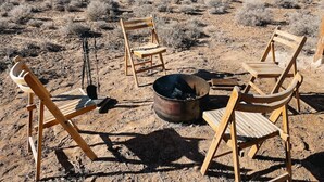 Un paysage désertique avec des chaises en bois et un feu de camp.