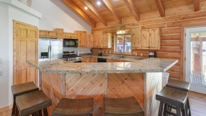 Una cocina con gabinetes de madera, encimera de granito y taburetes de bar.