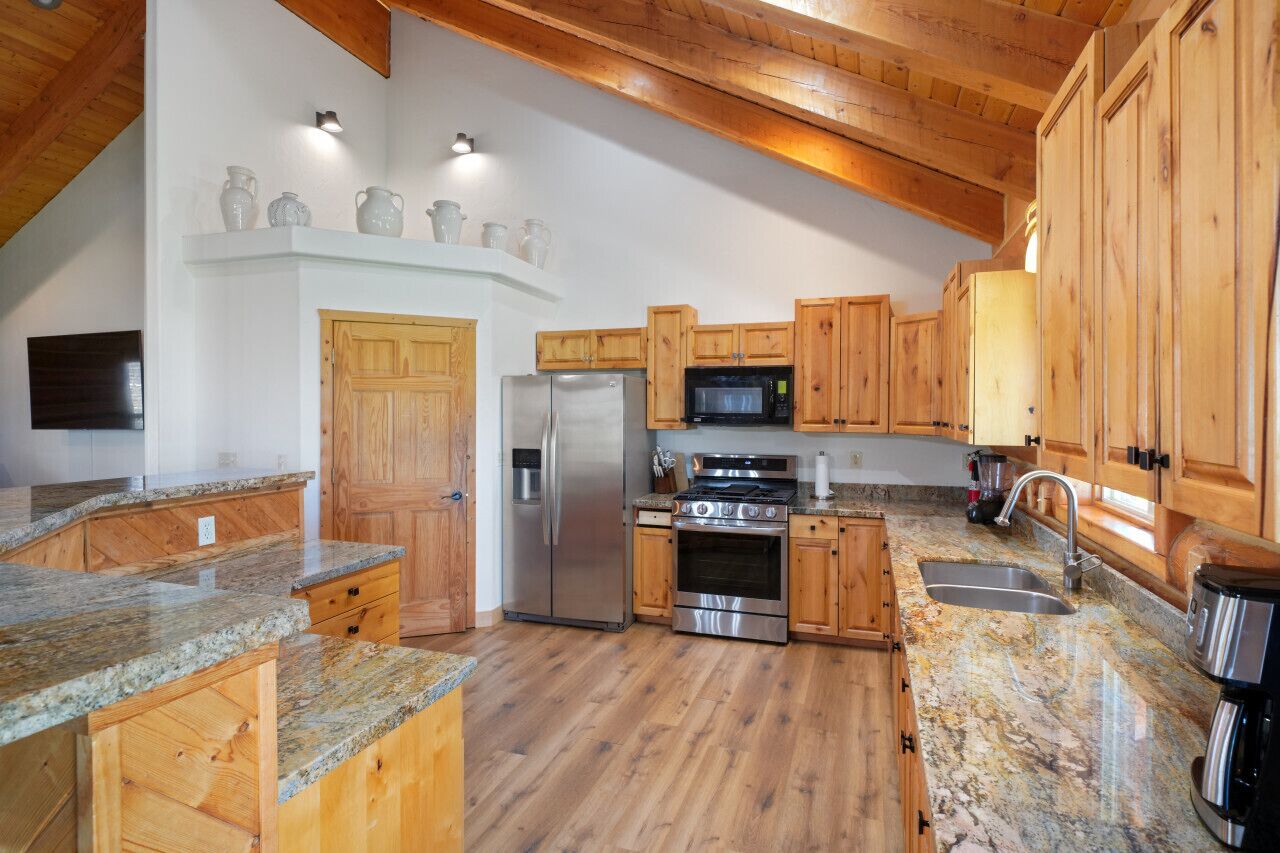 A kitchen with wooden cabinets, granite countertops, a stainless steel refrigerator, a microwave, and an oven.