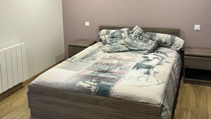 Een slaapkamer met een bed, een nachtkastje en een wandlamp.
