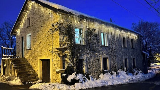 Een stenen huis met een sneeuwbedekte dak en een trap naar de ingang.