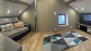 Een moderne woonkamer met een hoekbank, een flatscreen televisie en een geometrisch vloerkleed.