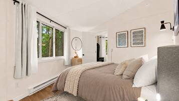 Una camera da letto con un letto, comodino, lampada e vista sul verde circostante.