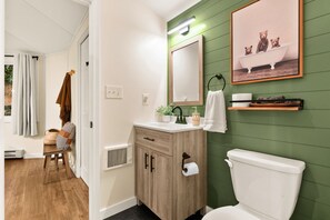 A bathroom with a wooden cabinet, a toilet, a mirror, and a green wall.