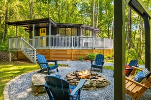 A cabin with a deck, outdoor seating, and a fire pit.