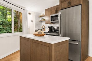 A modern kitchen with a large island, stainless steel appliances, and wooden cabinets.