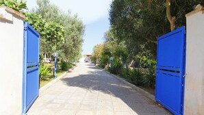 A paved pathway flanked by blue gates leading to a building. - Myrtle House1318 (Torre Pali)