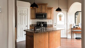 A kitchen with wooden cabinets, a built-in microwave, and pendant lighting. - Charming home walking distance from downtown Kanab, w/King Suite (Kanab)