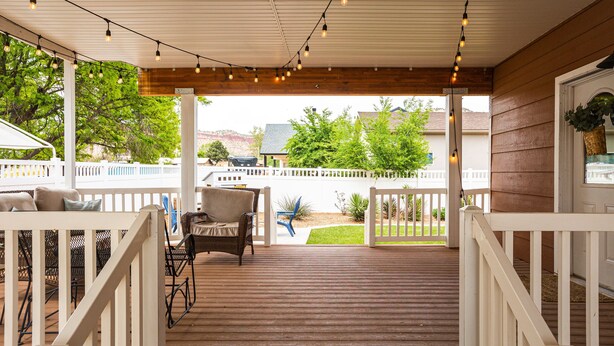 A covered deck with string lights, wooden railings, and outdoor furniture. - Charming home walking distance from downtown Kanab, w/King Suite (Kanab)