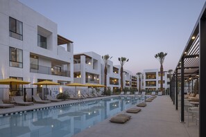 Un hotel moderno con piscina, tumbonas y sombrillas.