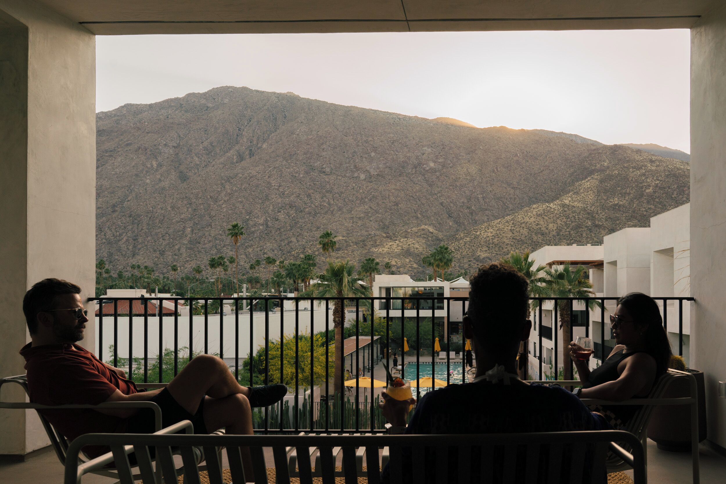 A balcony with a view of mountains and a pool area.