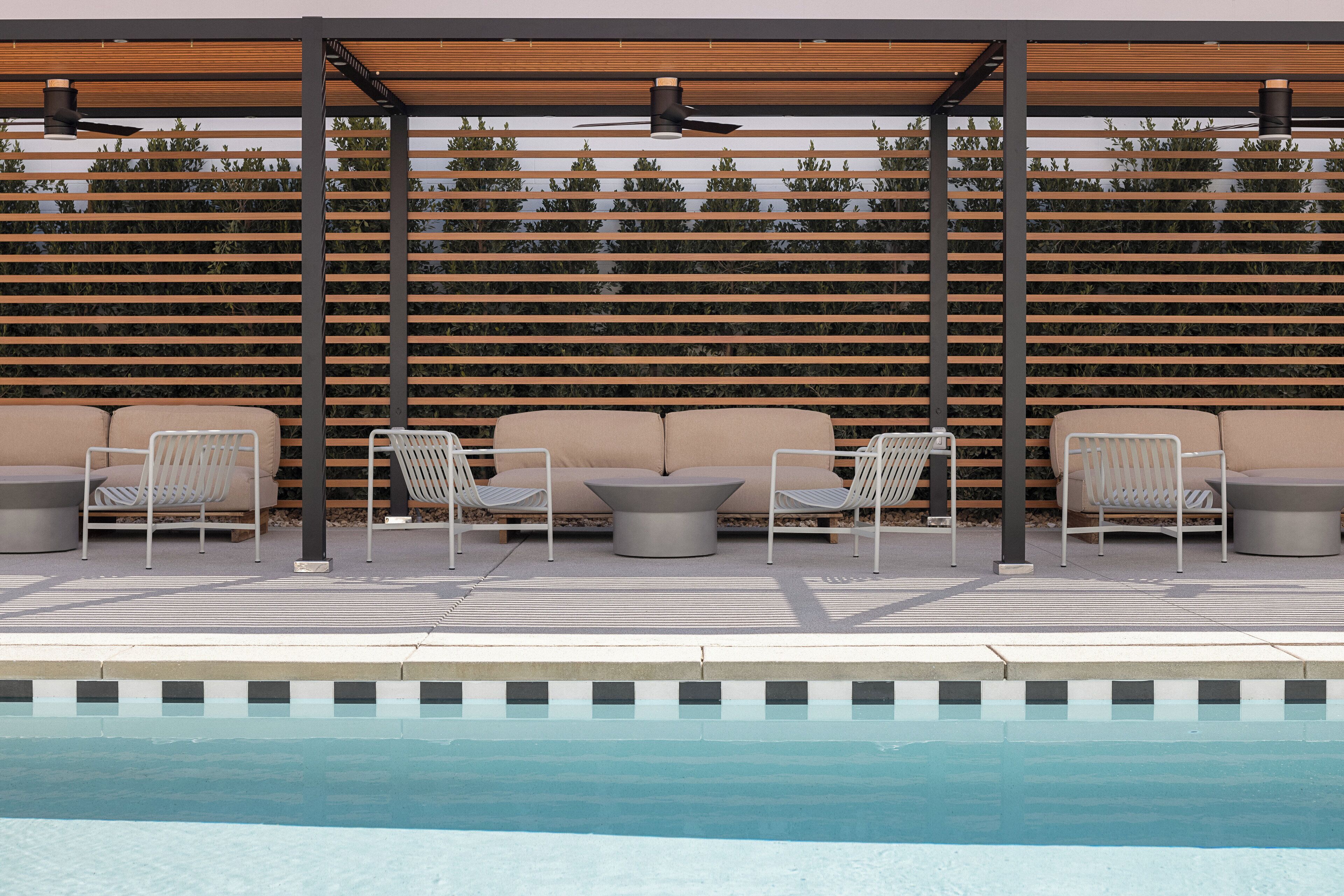Un espace aménagé au bord de la piscine, comprenant une pergola, des chaises longues et un coin salon avec des coussins.