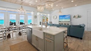 A modern kitchen with a large island, white cabinetry, and pendant lighting. - Newly Built Luxury 5- bedroom Beachfront Villa with Infinity Heated Pool (Exuma)