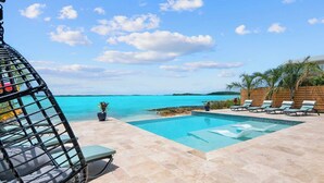 A pool area with lounge chairs and a view of the ocean. - Newly Built Luxury 5- bedroom Beachfront Villa with Infinity Heated Pool (Exuma)