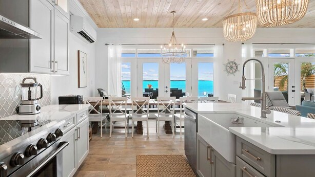 A modern kitchen with a large island, stainless steel appliances, and a view of the ocean. - Newly Built Luxury 5- bedroom Beachfront Villa with Infinity Heated Pool (Exuma)