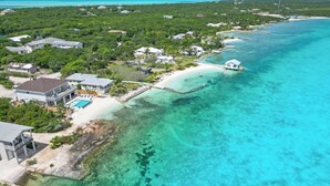 An aerial view of a coastal property with a beach, clear turquoise waters, and lush greenery. - Newly Built Luxury 5- bedroom Beachfront Villa with Infinity Heated Pool (Exuma)